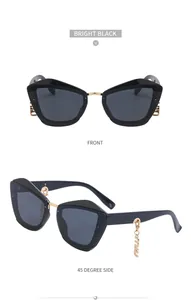 Détail de lunettes de soleil œil-de-chat avec pendentifs dorés et monture noire