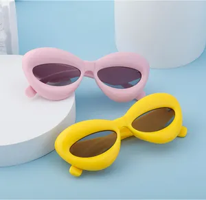 Close-up of stylish lip-shaped sunglasses in pink and yellow on minimalist pedestals