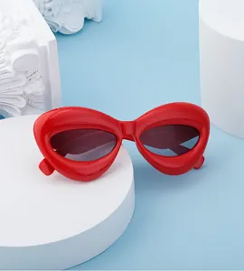 Detail view of bold red bubble frame sunglasses with dark lenses on a blue backdrop