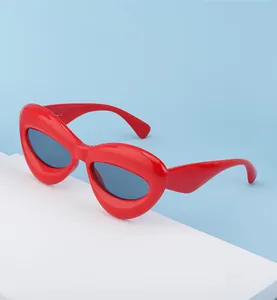 Close-up of stylish red lip-shaped sunglasses with dark lenses on a white display pedestal