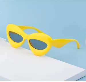 Detail of yellow chunky lip-shaped sunglasses with dark lenses on a blue background