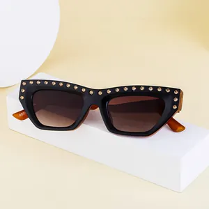 Chic cat-eye sunglasses with gold rhinestones and black frames on a white platform