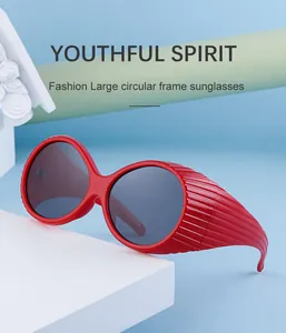 Detail of red large circular frame sunglasses with striped side temples on a blue backdrop