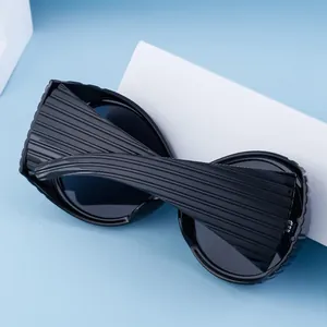 Detail of black oval sunglasses with unique pleated texture on frames and temples