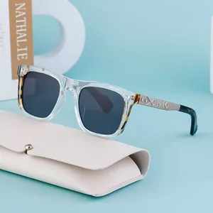 Square clear frame sunglasses with metal temples and a beige leather case on blue background