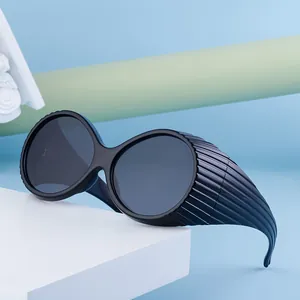 Fashionable black oval oversized sunglasses with side striped texture on a white stand