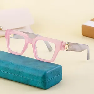 Gafas cuadradas rosa traslúcido con patillas de mármol sobre un estuche de cuero turquesa