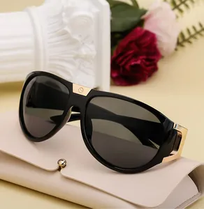 Detail of black sports sunglasses with gold accents resting on a leather case