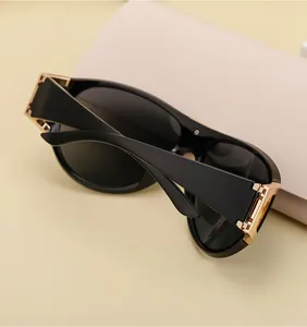 Close-up of black sports sunglasses with gold hinge details on a beige background