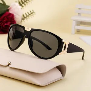 Black oversized sunglasses with gold accents and a cream leather storage case