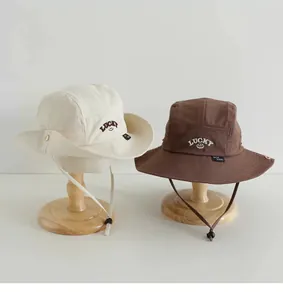 Detailansicht der Kinder-Fischerhüte in Beige und Braun mit LUCKY-Lächeln-Stickerei