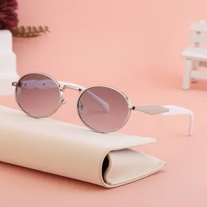 Oval silver metal sunglasses with pink lenses and white temples on a pastel pink background