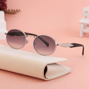 Retro oval sunglasses with silver metal frame and purple gradient lenses on a cream case