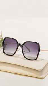 Close-up of black square sunglasses with TAC polarized lenses on a beige leather pouch