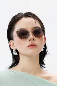 Cat-eye tortoiseshell sunglasses and glossy silver dome earrings on a model in knit top