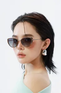 Detail of cat eye sunglasses with tortoise shell trim and silver sphere earrings