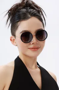 Close-up of stylish round polarized sunglasses with gold metal frames on a female model