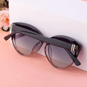 Detail of black cat-eye sunglasses with gold metal hinges and gradient grey lenses
