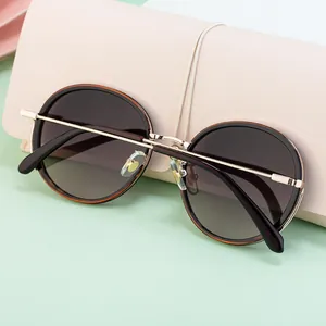 Close-up of retro round sunglasses with tortoise shell trim on a beige leather case