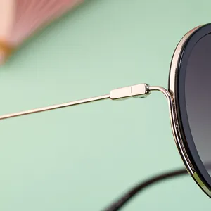Detailed close-up of premium gold metal hinge and frame joints on round sunglasses