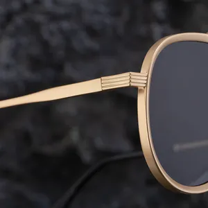 Detail of golden metal frame hinges and dark grey lenses of aviator sunglasses