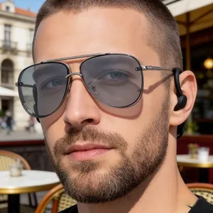Close-up of men's silver aviator sunglasses and ear-worn device in outdoor setting