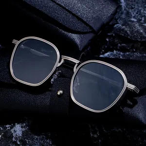 Square metal frame sunglasses with dark lenses and black leather case on stone