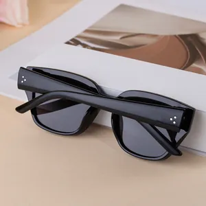 Détail de lunettes de soleil carrées noires avec rivets argentés à trois points