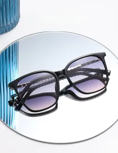 Detail of square black sunglasses with purple gradient lenses and gold chain hinge