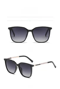 Close-up of square black sunglasses with grey gradient lenses and gold beaded temples