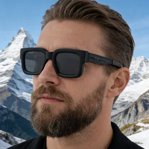 Detail of square matte black sunglasses with embossed temples against snowy mountains
