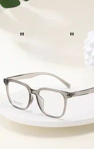 Detail einer quadratischen transparent grauen Optikbrille mit Text auf weißem Sockel