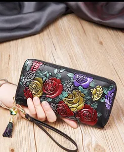 Détail d'un portefeuille en cuir noir avec motifs floraux en relief 3D et pompons