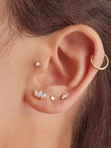 Macro detail of 5-piece gold ear set with opal stud and star piercings on ear