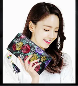 Detail of floral embossed leather wallet featuring colorful roses and floral tassel charm