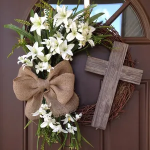 Rustic Easter wreath with white lilies, burlap bow and wooden cross on a brown door
