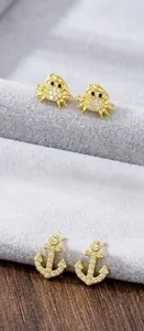 Detailed view of gold plated nautical stud earrings with crab and anchor crystal designs