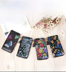 Detail of genuine cowhide long wallets featuring embossed floral patterns and metal zippers
