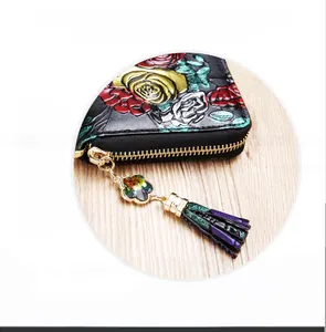 Detail of black leather wallet with floral embossing, purple tassel, and crystal zipper