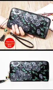 Detail of black embossed leather wallet with silver rose pattern and fringe wrist strap