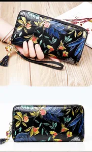 Detail of leather wallet with colorful floral embossing, wrist strap, and tassel charm