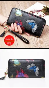 Detail of black leather long wallet featuring colorful butterfly embossing and floral tassel