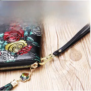 Detail of floral embossed leather wallet with wrist strap and crystal flower tassel