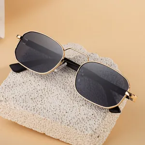 Modern square metal frame sunglasses with gold finish and dark lenses on mineral stone