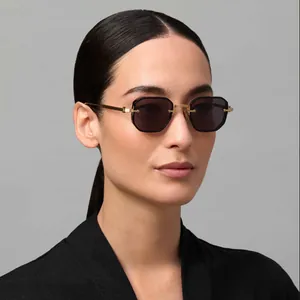 Detail of octagonal grey lenses and golden C-shaped metal hinges on sunglasses