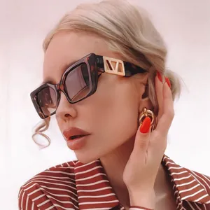 Detail of square tortoiseshell sunglasses featuring golden V-shaped metal logo on temple