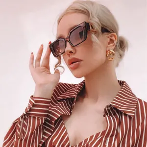 Detail of tortoise shell rectangular sunglasses and twisted gold link earrings worn by model