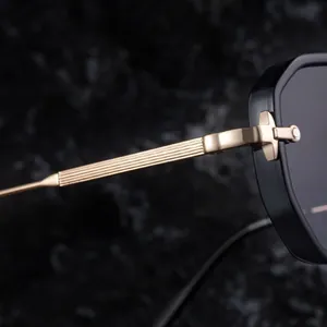 Detail of square sunglasses with gold metal temples and cross-shaped decorative hinge