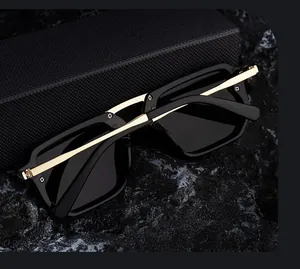 Detail of square sunglasses with gold metal temples on a textured black rock surface