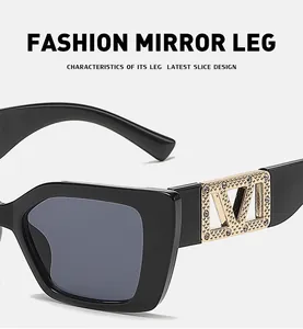 Close-up of black rectangular sunglasses featuring gold metal temples with diamond accents